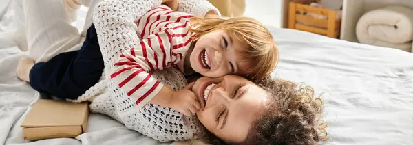 A mother and daughter embrace playfully on a cozy bed, sharing a joyful connection, banner — Stock Photo