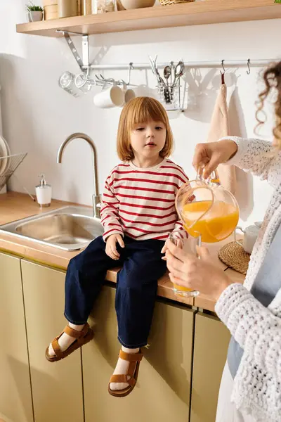 Enjoying a sunny day, a mother pours refreshing juice for her daughter while cooking. — Stock Photo