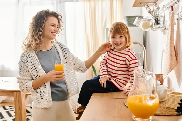 Mère et fille partagent le rire et une boisson rafraîchissante dans leur espace de vie confortable. — Photo de stock