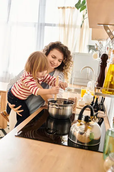 Curly-haired mother and daughter share a delightful cooking experience in their cozy kitchen. — Stock Photo