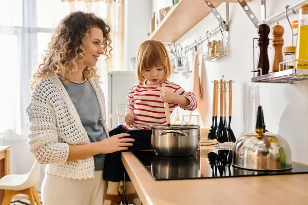 Curly mother and daughter share laughter while cooking together in a bright kitchen at home. — Stock Photo