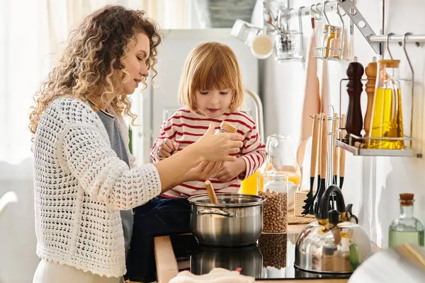 Together, a curly-haired mother and her daughter engage in joyful cooking at home, sharing smiles. — Stock Photo