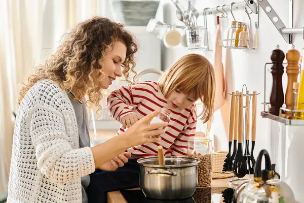 Curly-haired mother and daughter bond as they cook together in their cozy kitchen during the day. — Stock Photo