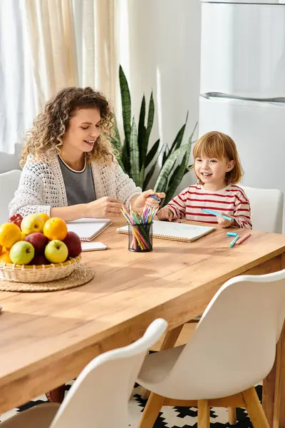 Uma mãe e filha alegremente criar juntos em sua mesa de cozinha colorida. — Fotografia de Stock
