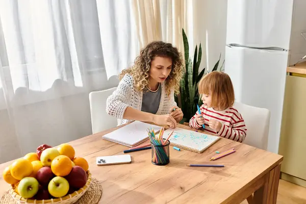 Mãe e filha desfrutar de um tempo de qualidade desenho com canetas coloridas em sua mesa de cozinha aconchegante. — Fotografia de Stock
