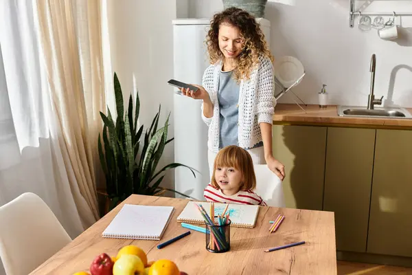 A mother engages with her daughter while they color and share moments in their inviting kitchen. — Stock Photo