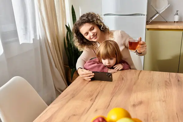 Curly-haired mother and daughter share a cozy moment together while enjoying technology at home. — Stock Photo