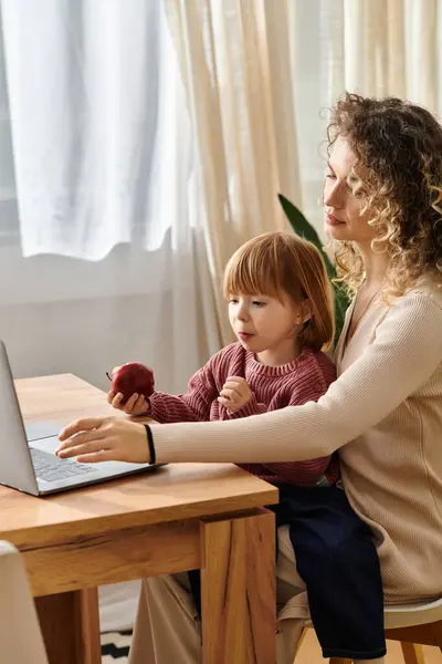 A curly-haired mother assists her daughter with online learning at the kitchen table. — Stock Photo