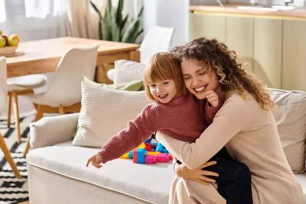 A loving moment unfolds as a mother and her daughter embrace, filled with laughter and joy at home. — Stock Photo