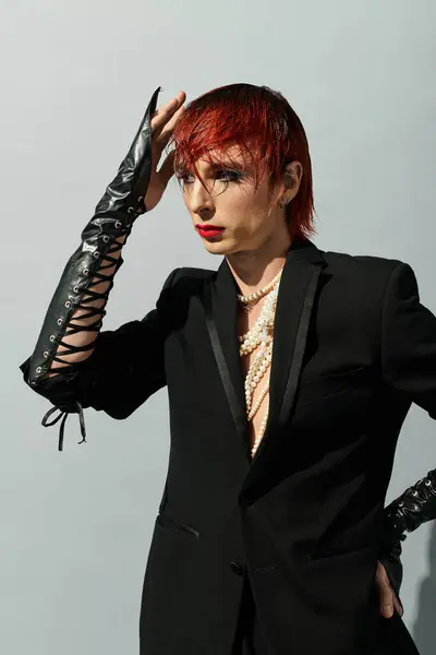 A young man styles his vibrant hair while wearing an elegant yet edgy outfit, exuding confidence. — Stock Photo