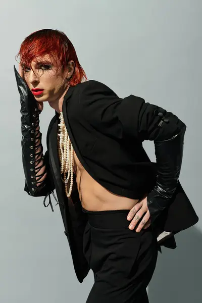 A confident young man showcases a bold fashion statement with striking red hair and unique attire. — Stock Photo