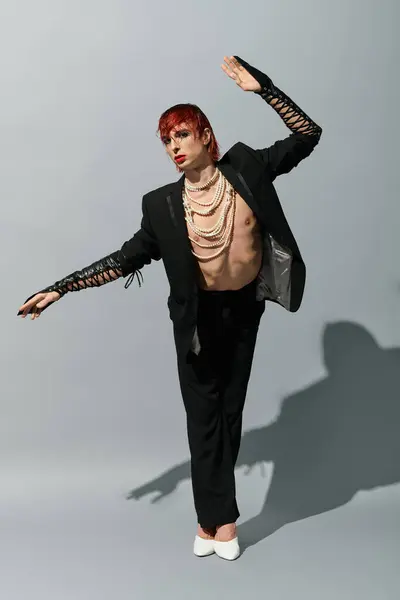 A young man stands confidently in a striking pose, displaying unique fashion choices and expression. — Stock Photo