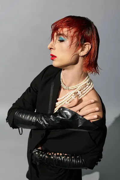 This young man stands confidently, displaying a bold fashion choice with striking makeup and pearls. — Stock Photo
