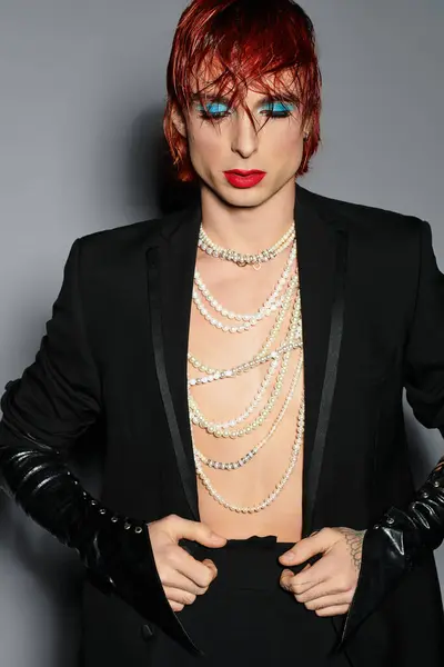 A young man with red hair wears bold blue makeup and elegant attire in a stylish setting. — Stock Photo