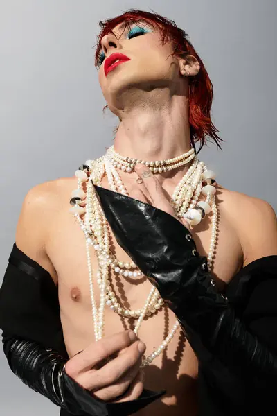 A young man with striking features displays a creative look adorned with pearls and vibrant makeup. — Stock Photo