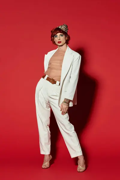 Junger Mann posiert selbstbewusst in stylischem Outfit vor knallroter Wand und strahlt Charisma und Flair aus. — Stockfoto