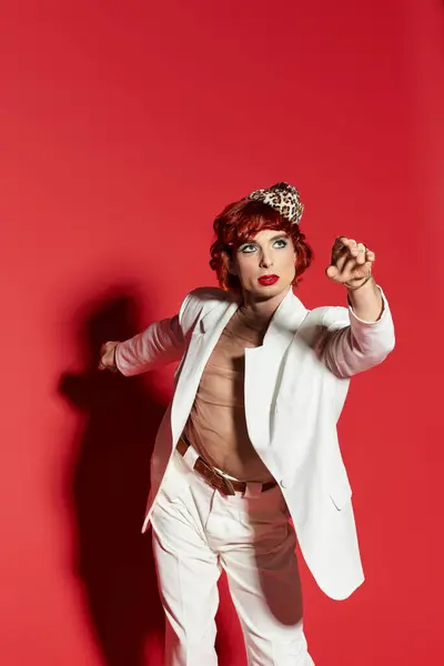 A young man flaunts a playful style against a bold red backdrop, brimming with confidence. — Stock Photo