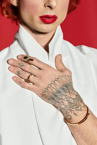 A young man displays his artistic tattoos and fashion sense against a vivid red backdrop. — Stock Photo