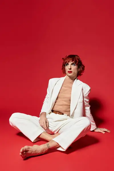 A young man with vibrant red hair sits gracefully on the floor, showcasing his stylish look. — Stock Photo