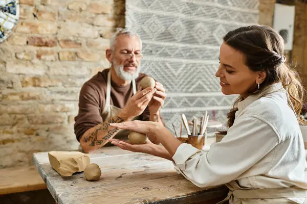 A mature couple enjoys quality time shaping clay together in a pottery class. — Stock Photo