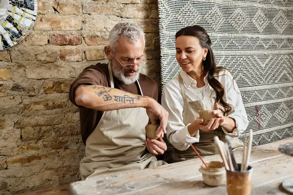 A mature couple enjoys quality time together in a pottery class, shaping clay with joy. — Stock Photo