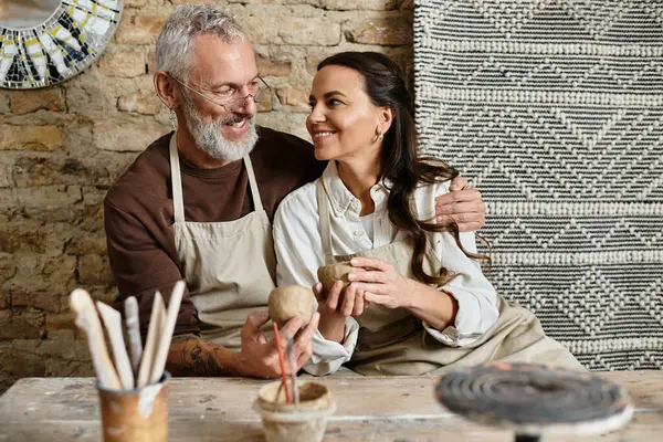 Una hermosa pareja disfruta moldeando arcilla en una clase de cerámica, compartiendo momentos de alegría y conexión. - foto de stock