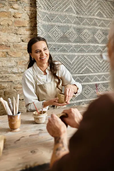 Una coppia matura modella gioiosamente l'argilla in una classe di ceramica, approfondendo il loro legame.. — Foto stock