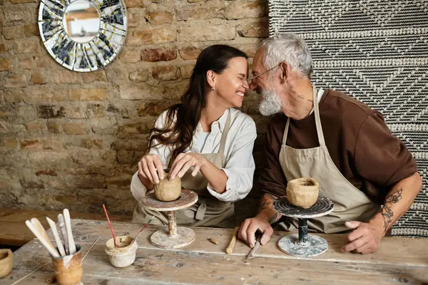 A beautiful mature couple enjoys a pottery class, shaping clay while sharing quality time. — Stock Photo