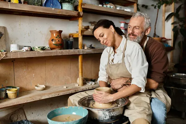 Mature couple enjoys quality time shaping clay during a pottery class, fostering connection. — Stock Photo
