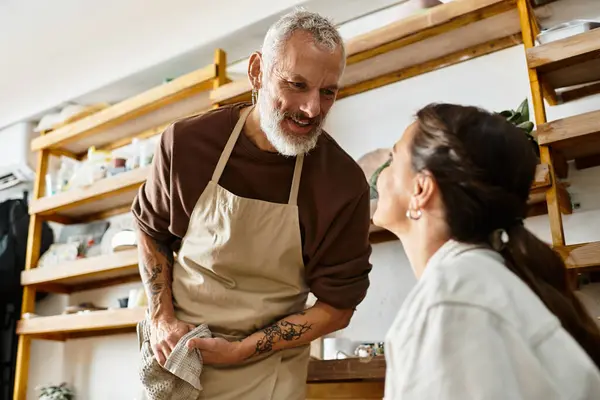 A beautiful mature couple enjoys their pottery class, shaping clay and sharing smiles together. — Stock Photo