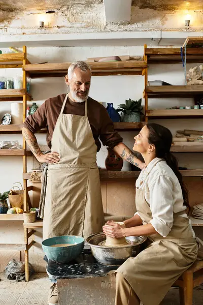 A mature couple enjoys shaping clay together during a pottery class, sharing smiles and love. — Stock Photo