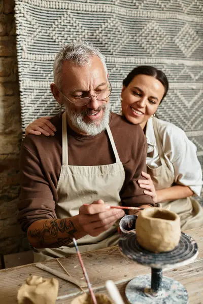 A mature couple joyfully shapes clay during a pottery class, celebrating their love. — Stock Photo