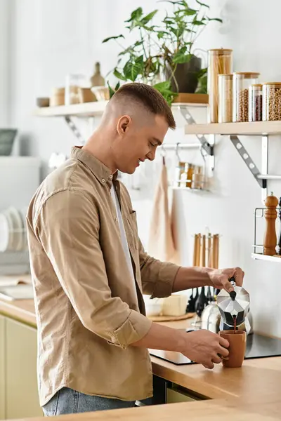 A young man in casual clothes prepares a fresh cup of coffee at home, embracing a cozy atmosphere. — Stock Photo