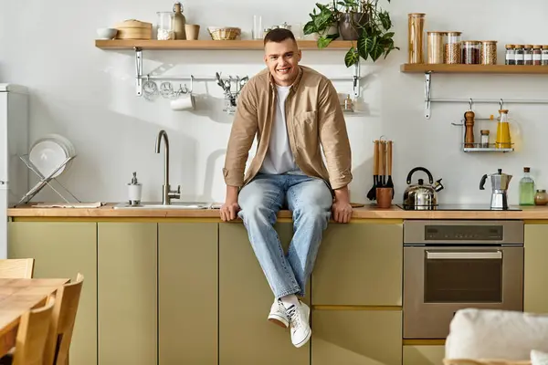 Relaxing in a modern kitchen, a young man shares a moment of joy in casual attire. — Stock Photo
