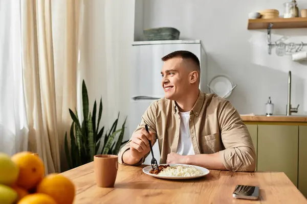 Handsome young man relaxes at home, savoring a delicious meal in a stylish living space. — Stock Photo