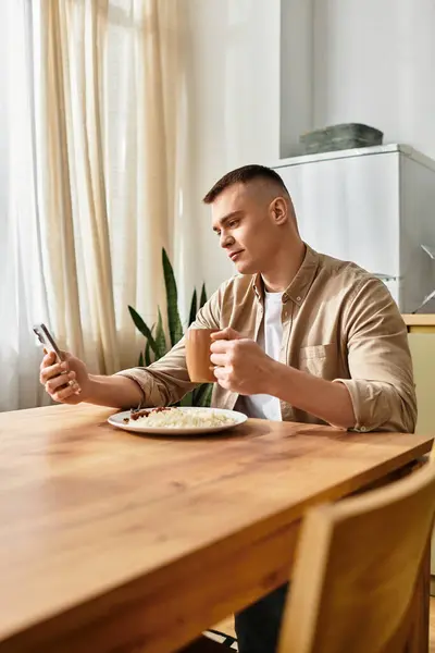 Casual breakfast time for a young man in his modern apartment while checking his phone. — Stock Photo