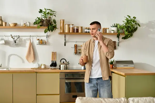 A young man in casual attire talks on the phone while enjoying his stylish apartment atmosphere. — Stock Photo