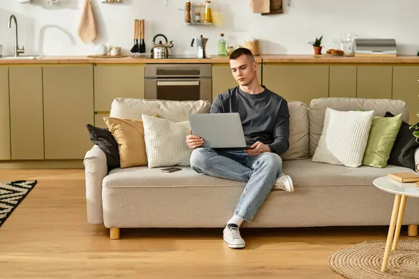 Casual moments of a young man enjoying his modern living space with a laptop on his lap. — Stock Photo