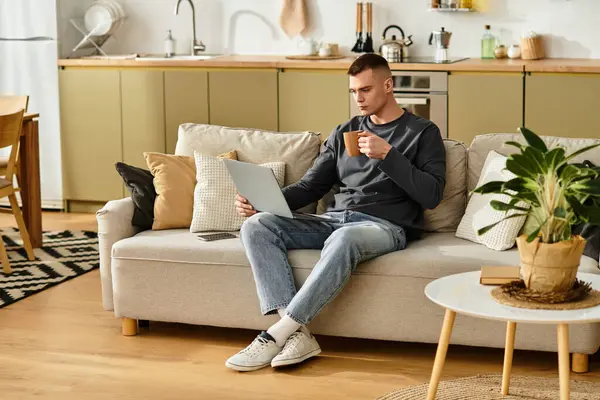 A young man enjoys some downtime in his stylish apartment while sipping coffee and browsing. — Stock Photo