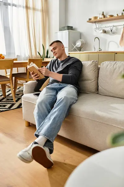 Young man enjoys a quiet moment at home reading a book in his stylish living space. — Stock Photo