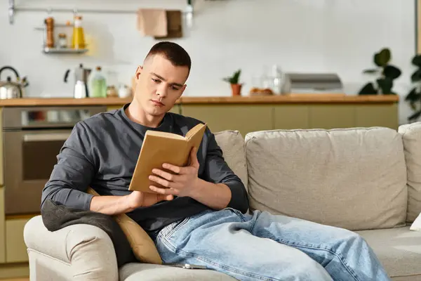 Casual moments unfold as a young man dives into a book, relaxed in his cozy apartment. — Stock Photo