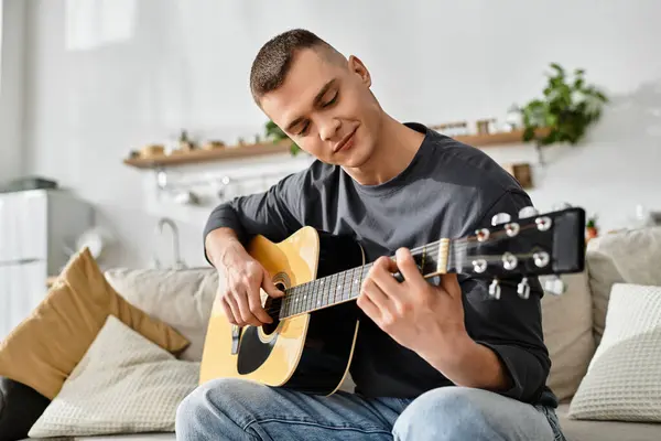 A young man relaxes in his stylish apartment playing guitar, embracing a casual lifestyle. — Stock Photo