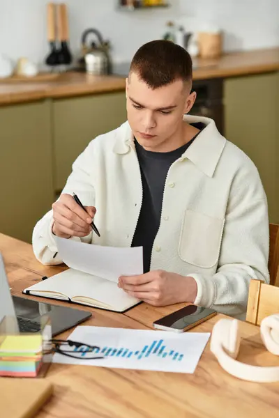 Handsome man in casual clothes studies documents at a wooden table in his stylish apartment. — Stock Photo