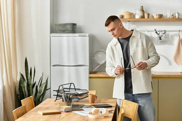 A stylish young man sits in a bright apartment, concentrating on his work with a laptop. — Stock Photo
