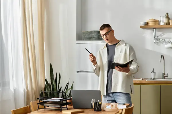 Handsome young man in casual clothes focuses on work while standing by his desk in a cozy apartment. — Stock Photo