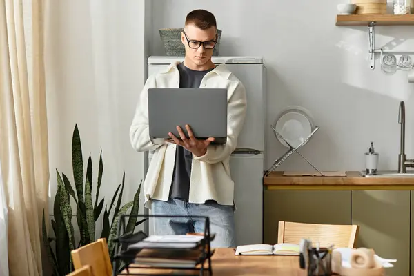 A handsome young man engages in remote work while standing in a stylish apartment setting. — Stock Photo