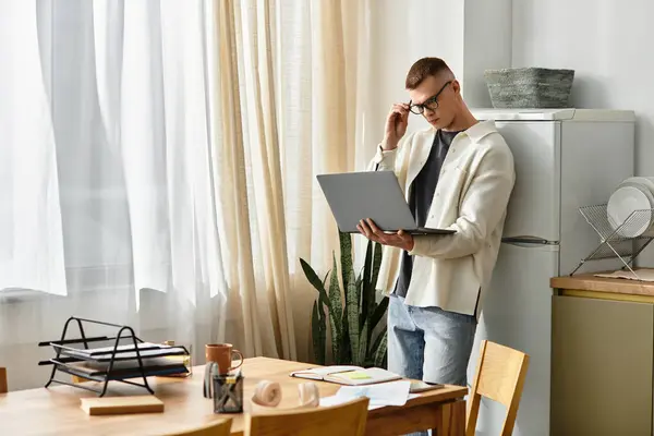 Handsome young man works from home, focused on his laptop in a modern, bright living space. — Stock Photo