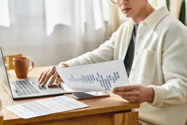 Cropped young man focuses on freelance projects while seated at his wooden desk. — Stock Photo