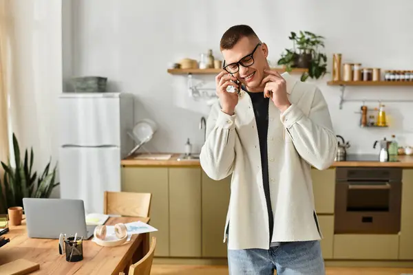 A young man in casual clothes smiles while working from home in a modern kitchen space. — Stock Photo