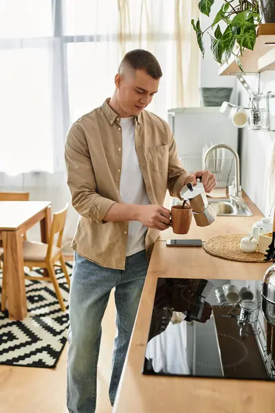 Casual young man brews coffee in his bright, modern kitchen, embracing a relaxed lifestyle at home. — Stock Photo